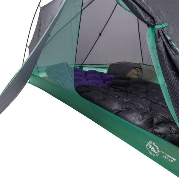 A close-up inside the Big Agnes Canada Pitchpine VST 1.5 shows sleeping bags and pads side by side on the floor, with mesh walls and an open door revealing its green and gray ultralight interior setup.