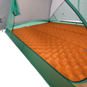 An orange inflatable sleeping pad covers the floor of the durable Big Agnes Canada Sarvis VST 3 tent, offering a cushioned sleeping surface inside this green and white shelter.