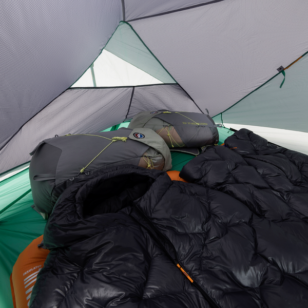 Black sleeping bag inside a tent with camping gear visible