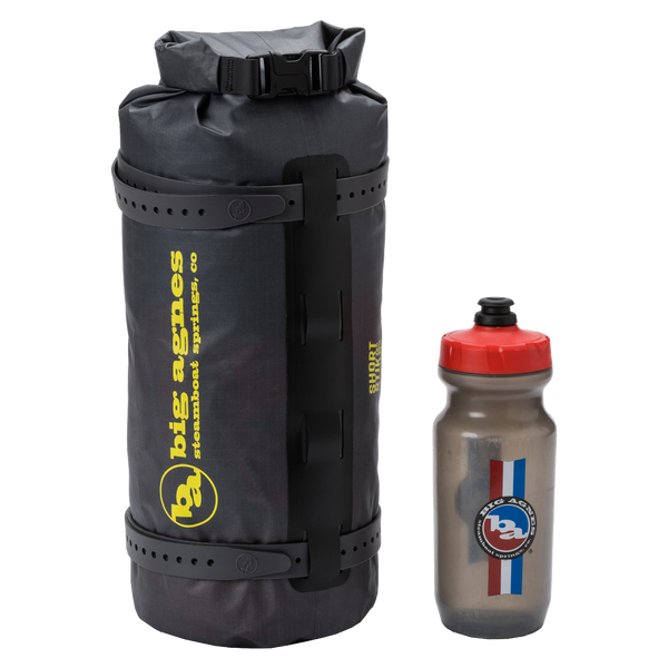 Black Tiger Wall UL2 Bikepack dry bag with yellow branding and a gray water bottle with red cap on a white background